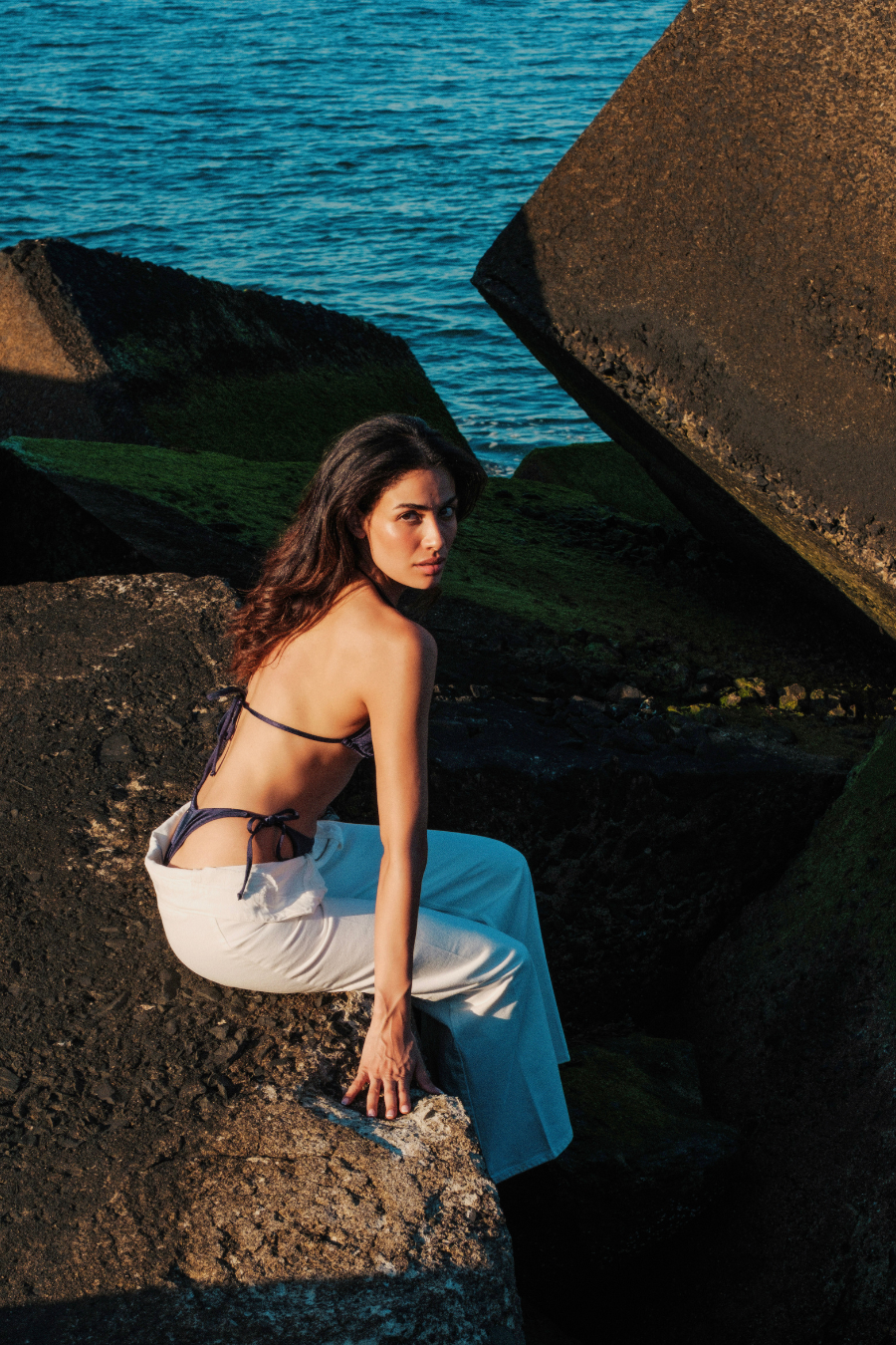 model op rots in donkerblauwe bikini met witte linnen broek open