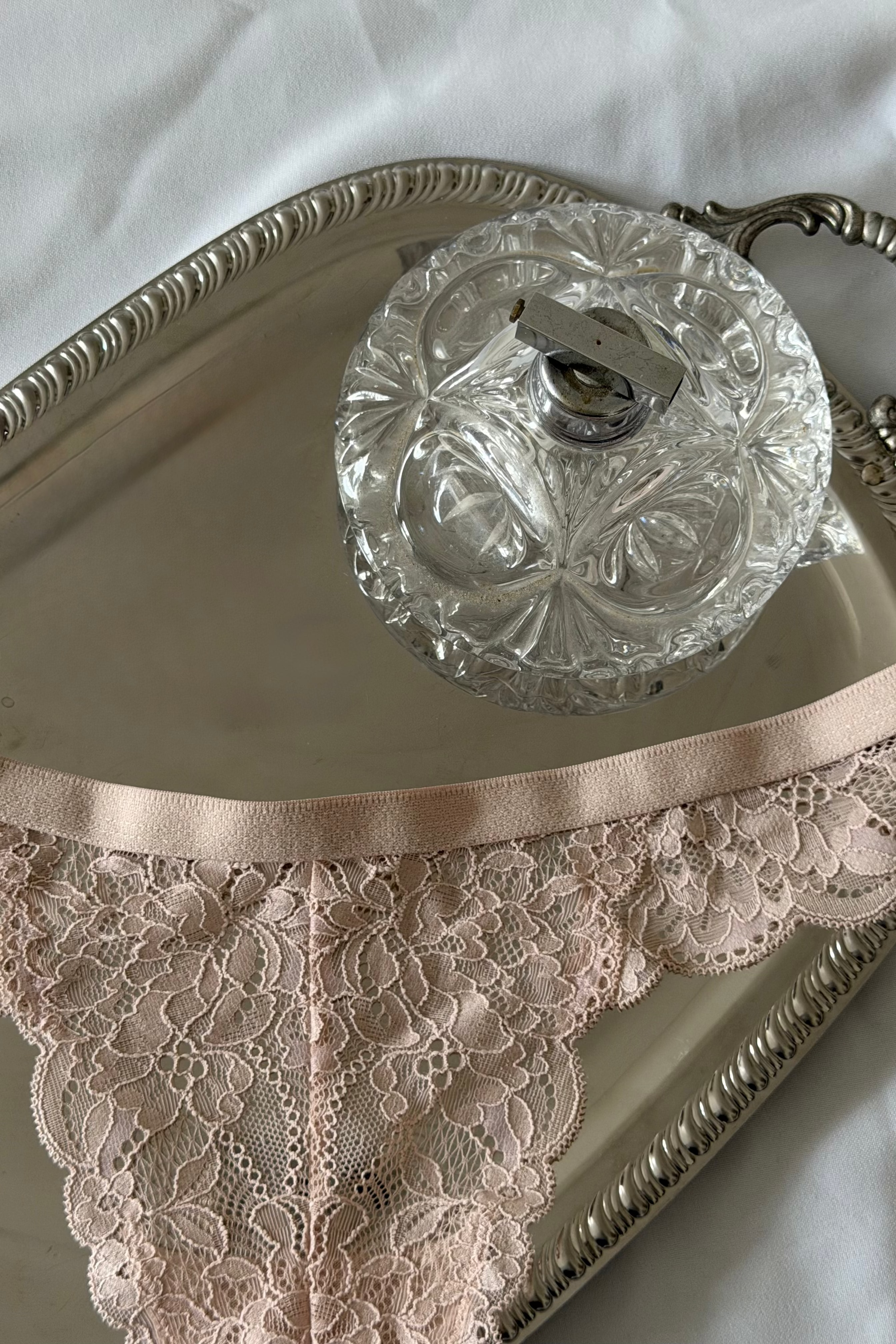 lichtroze string met kant op zilver dienblad op een bad 