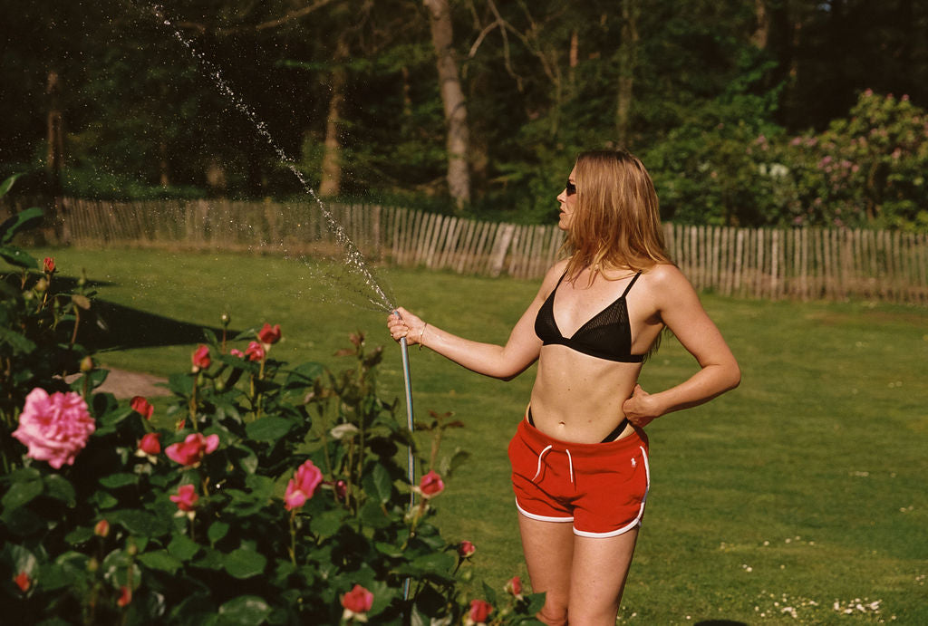 geraldine kemper geeft planten water in zwart bralette top en rood broekje