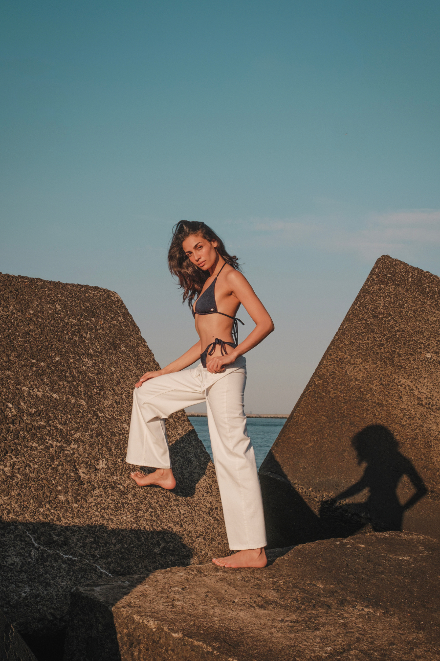 donkerblauwe bikini op model met rotsen op achtergrond